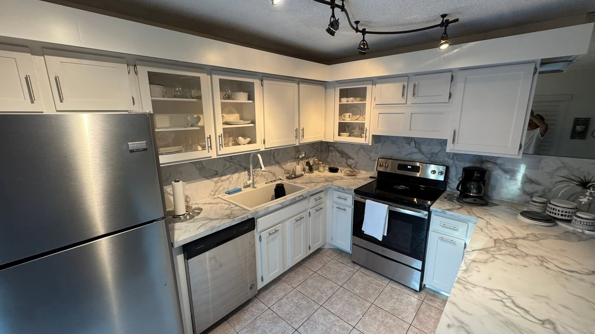 White kitchen cabinets with marble backsplash and stainless appliances, kitchen remodel in Port St. Lucie, FL by Dependable Guys LLC
